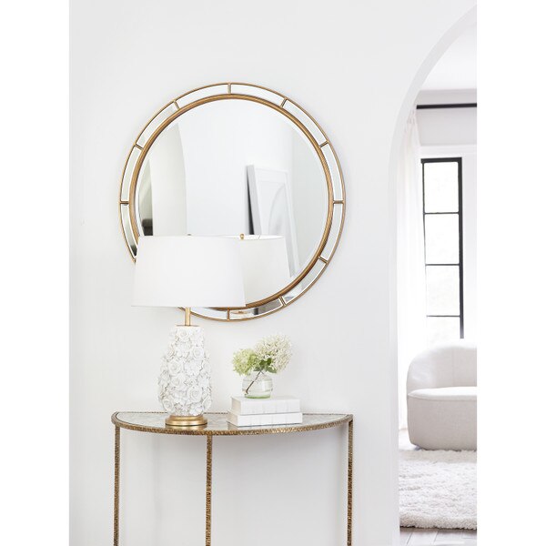 Living room wall with a gold beveled mirror and flower lamp